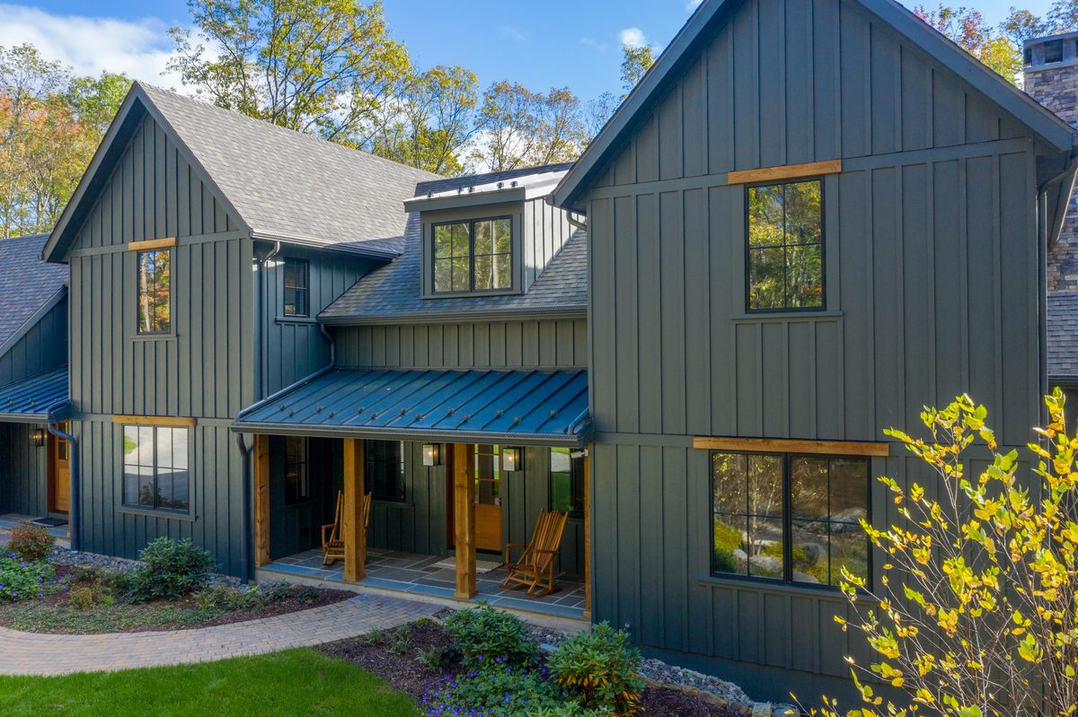 Board-and-batten fiber-cement siding home in deep green with a covered porch